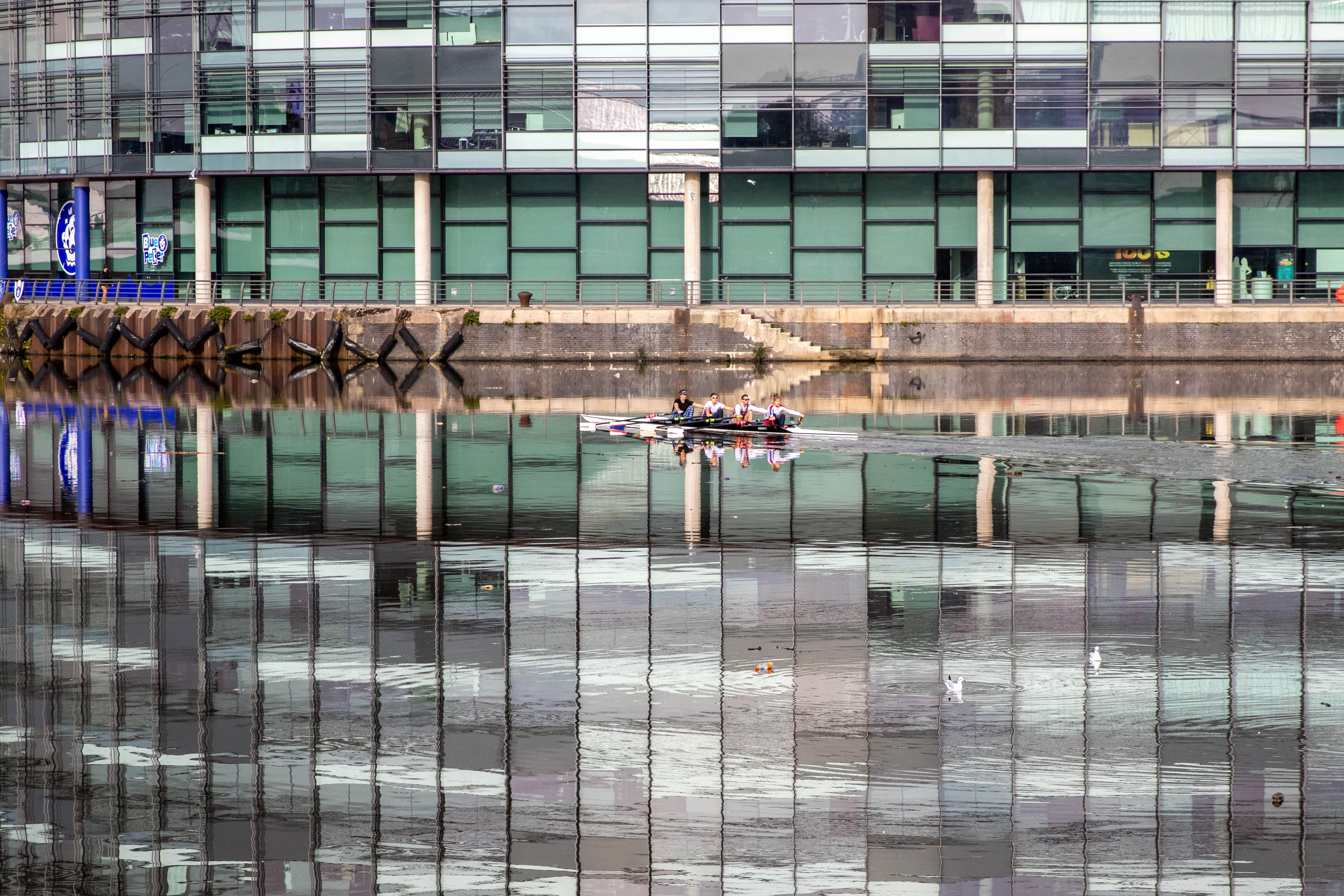 Rowers pass Media City in Salford Quays.