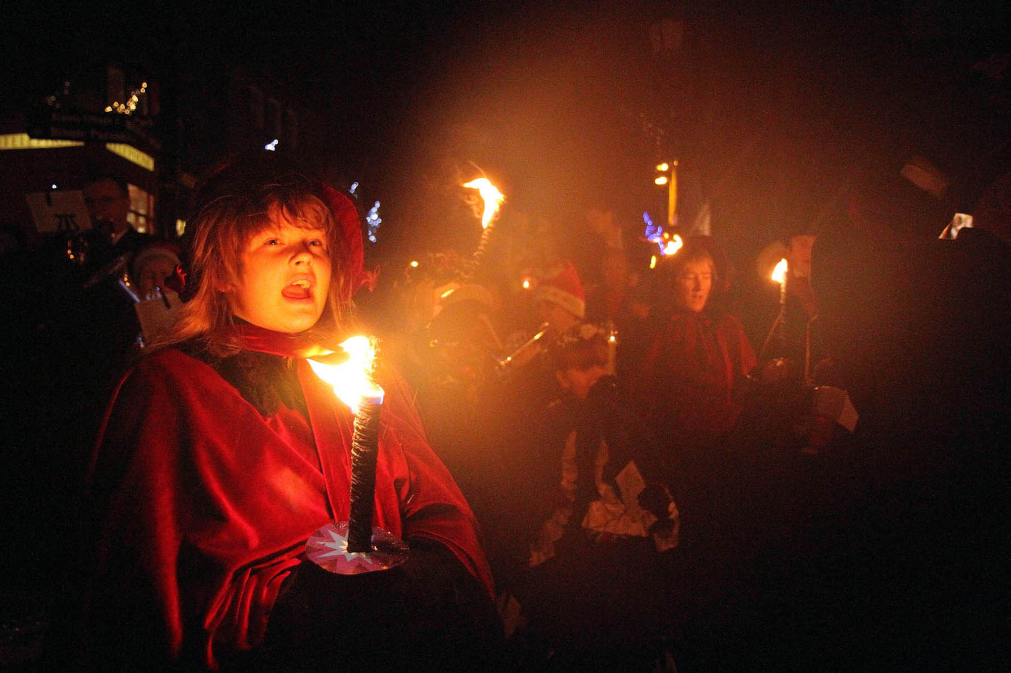 Torchlit parade participants sing carols on Main Street