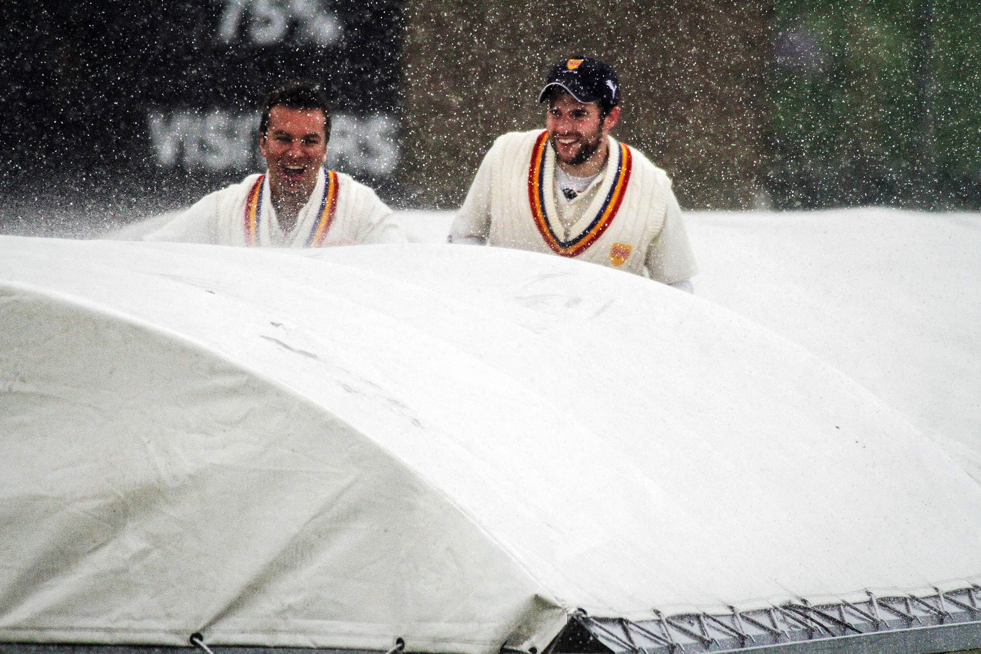 Steeton players still manage a smile as the covers go on during a deluge