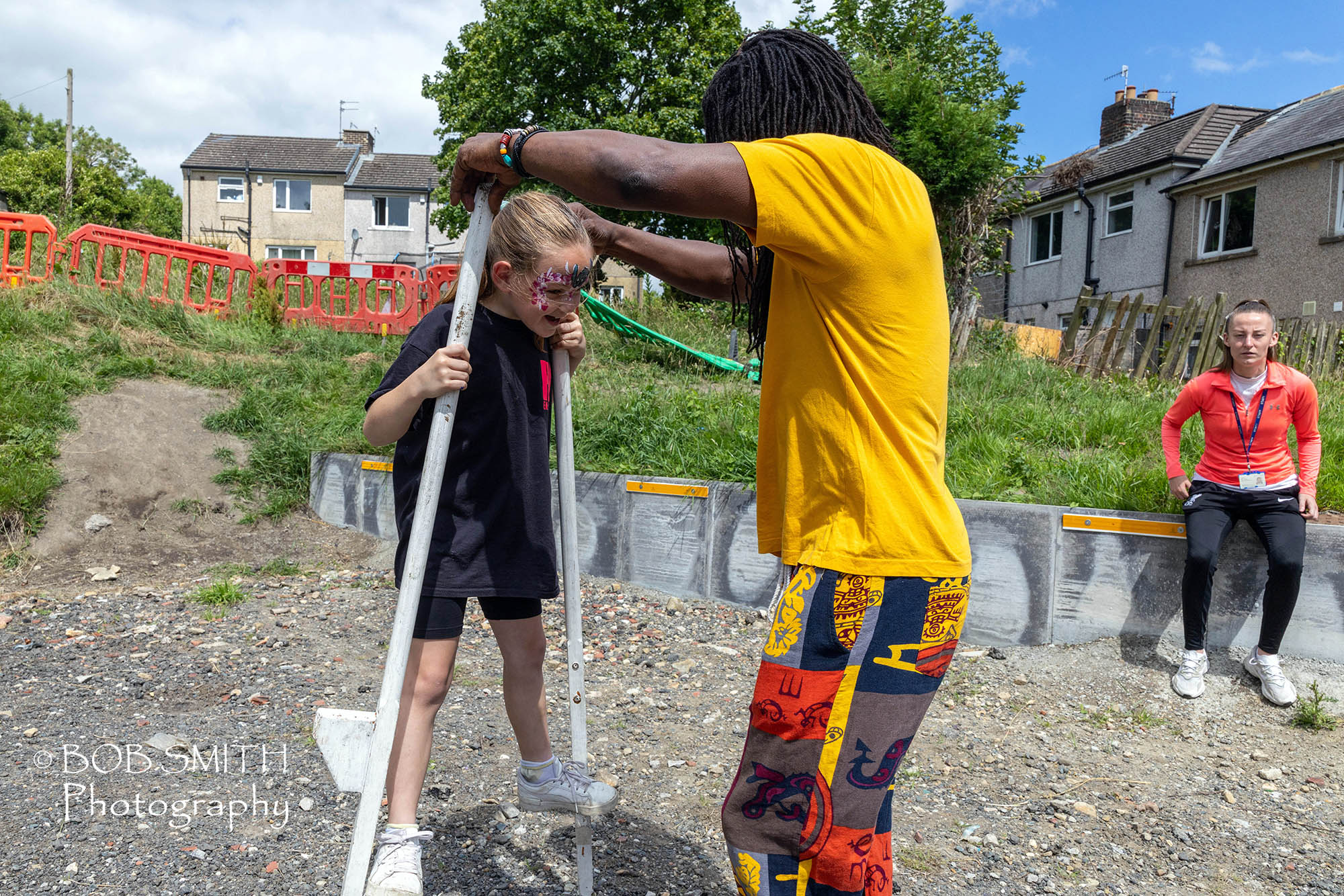 Bradford City of Culture 2025; K-Town People. Summer Sloan, nine, tries out the stilts, with help from bob samuels of Bradford Youth Service, at the Keith Thompson Centre garden party.