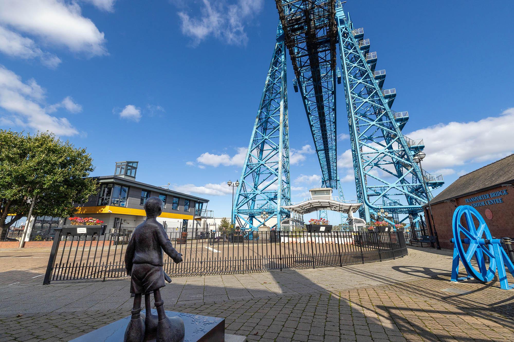 A sculpture is dwarfed by the giant latticework of the Middlesbrough Transporter Bridge